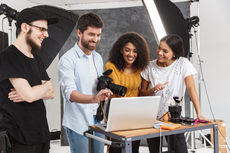 Portrait of fashion multiethnic people men and women looking at laptop while photo shooting with professional camera in studio